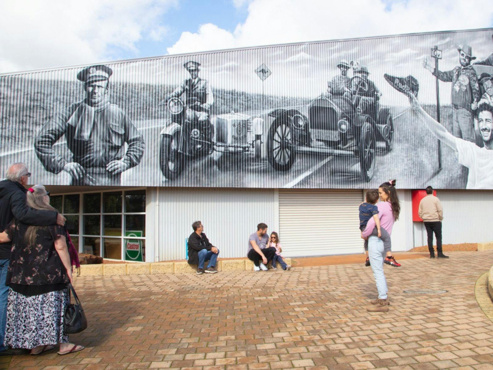 Group of people looking at the Motoring Legends of Western Australia mural found outside the museum