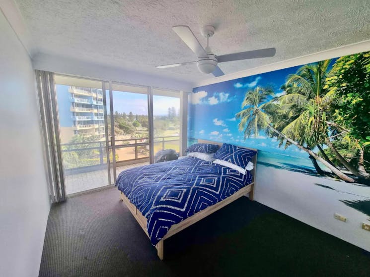 Master bedroom with Queen bed, ceiling fan and striking palm tree wallpaper
