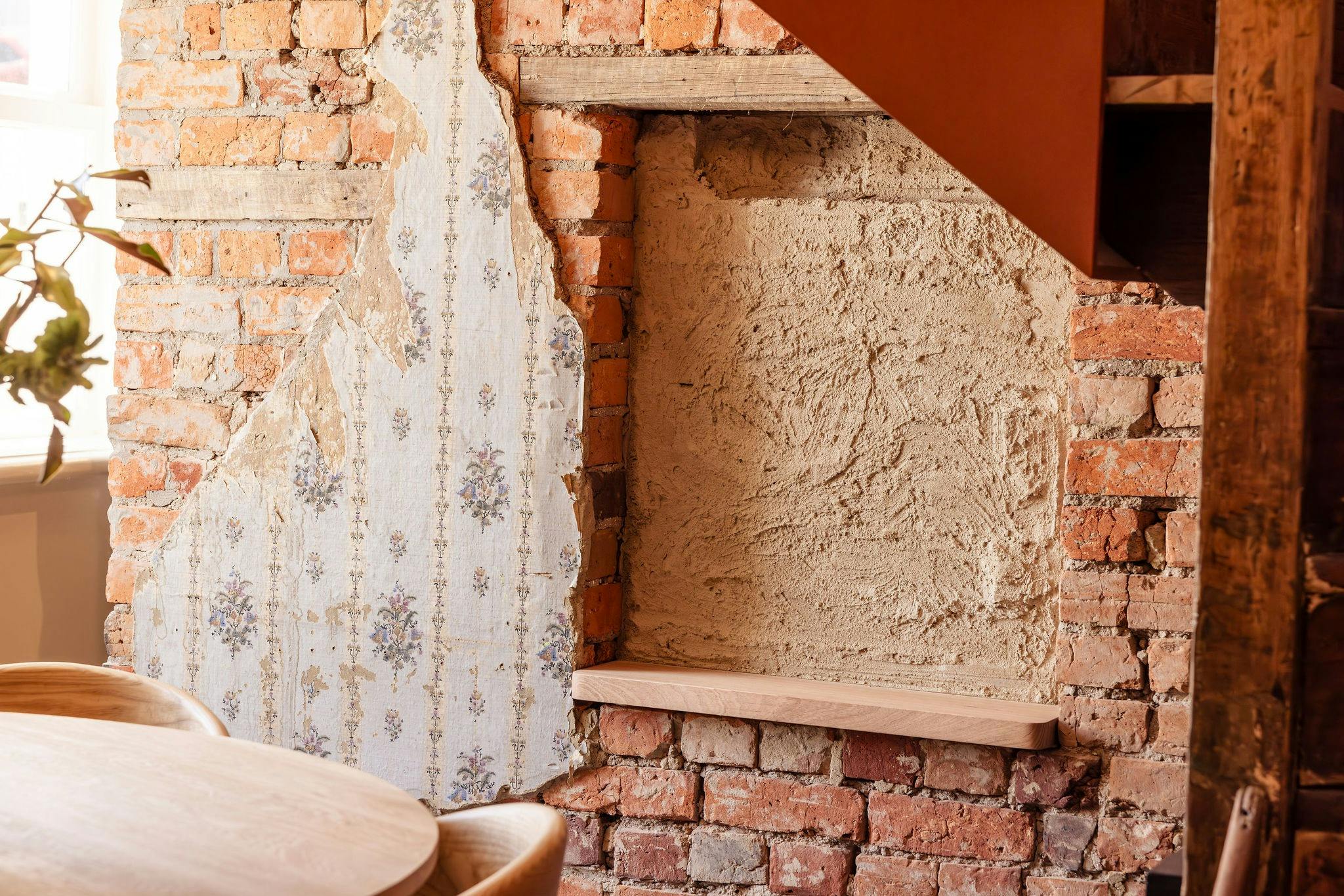dining room wall showcasing exposed brick and historic wallpaper