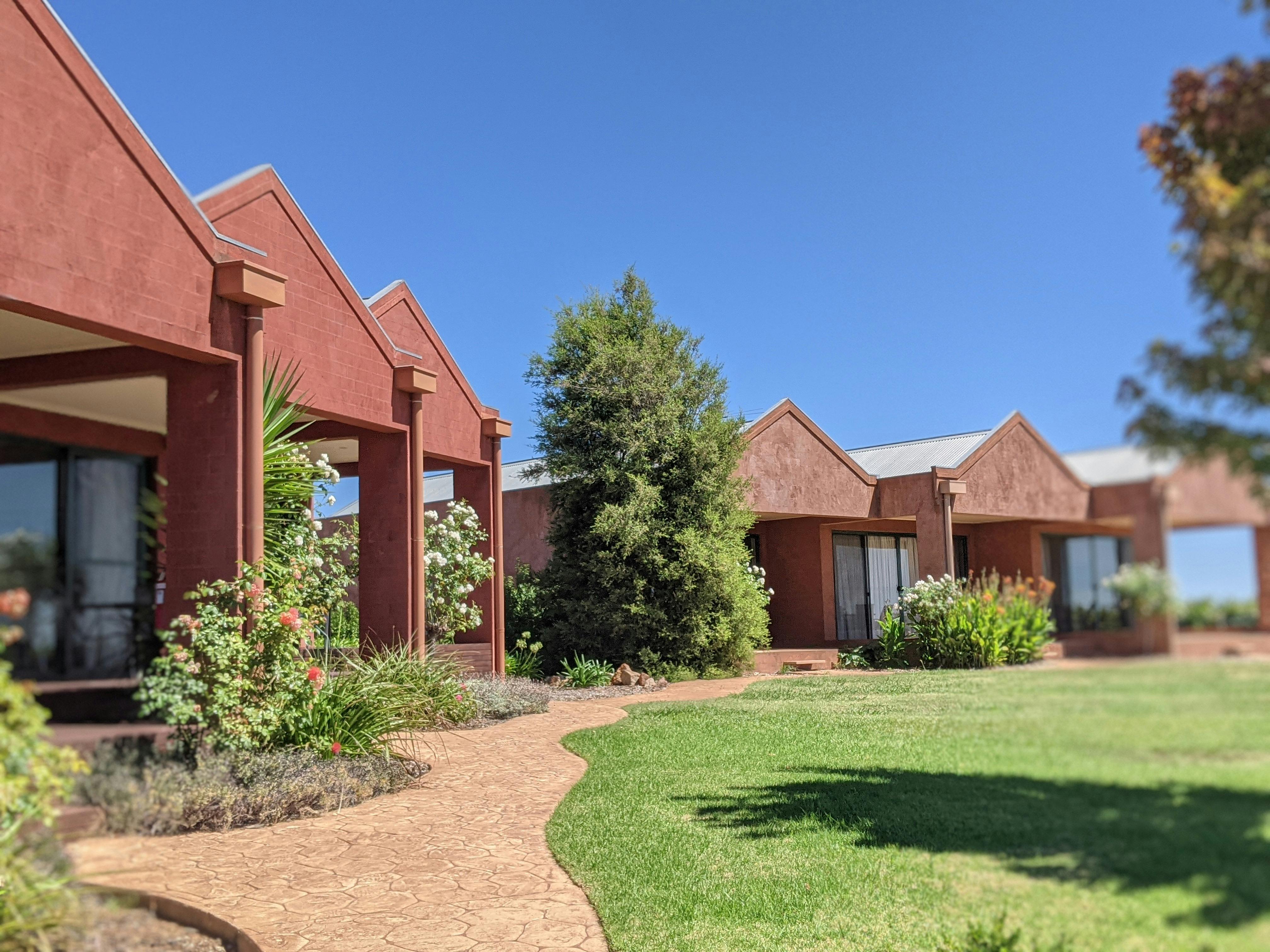 row of individual rooms with balcony overlooking grapevines