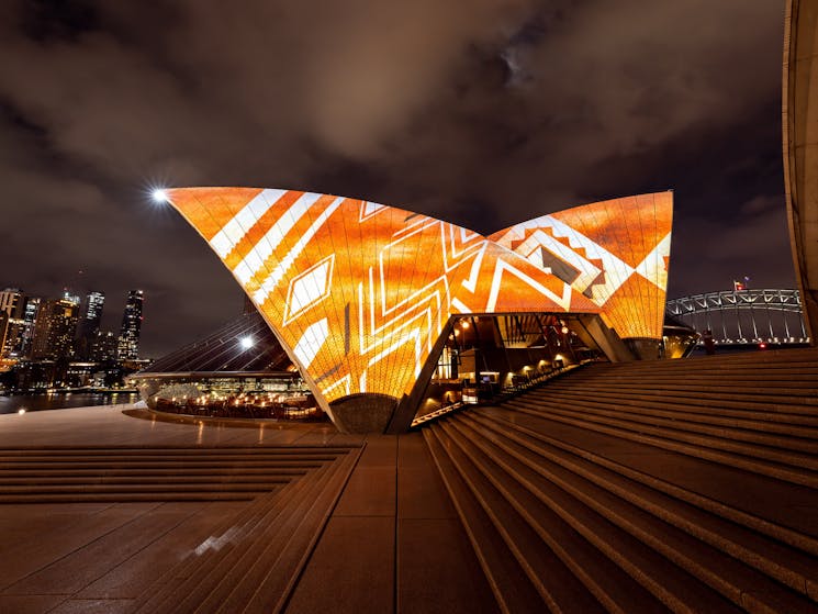 Bennelong sails illuminated with white and yellow patterns on an orange background
