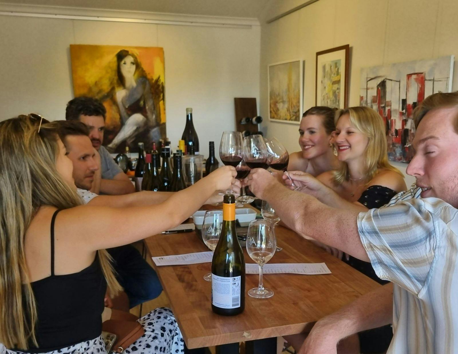 group of people at a table cheersing with red wine