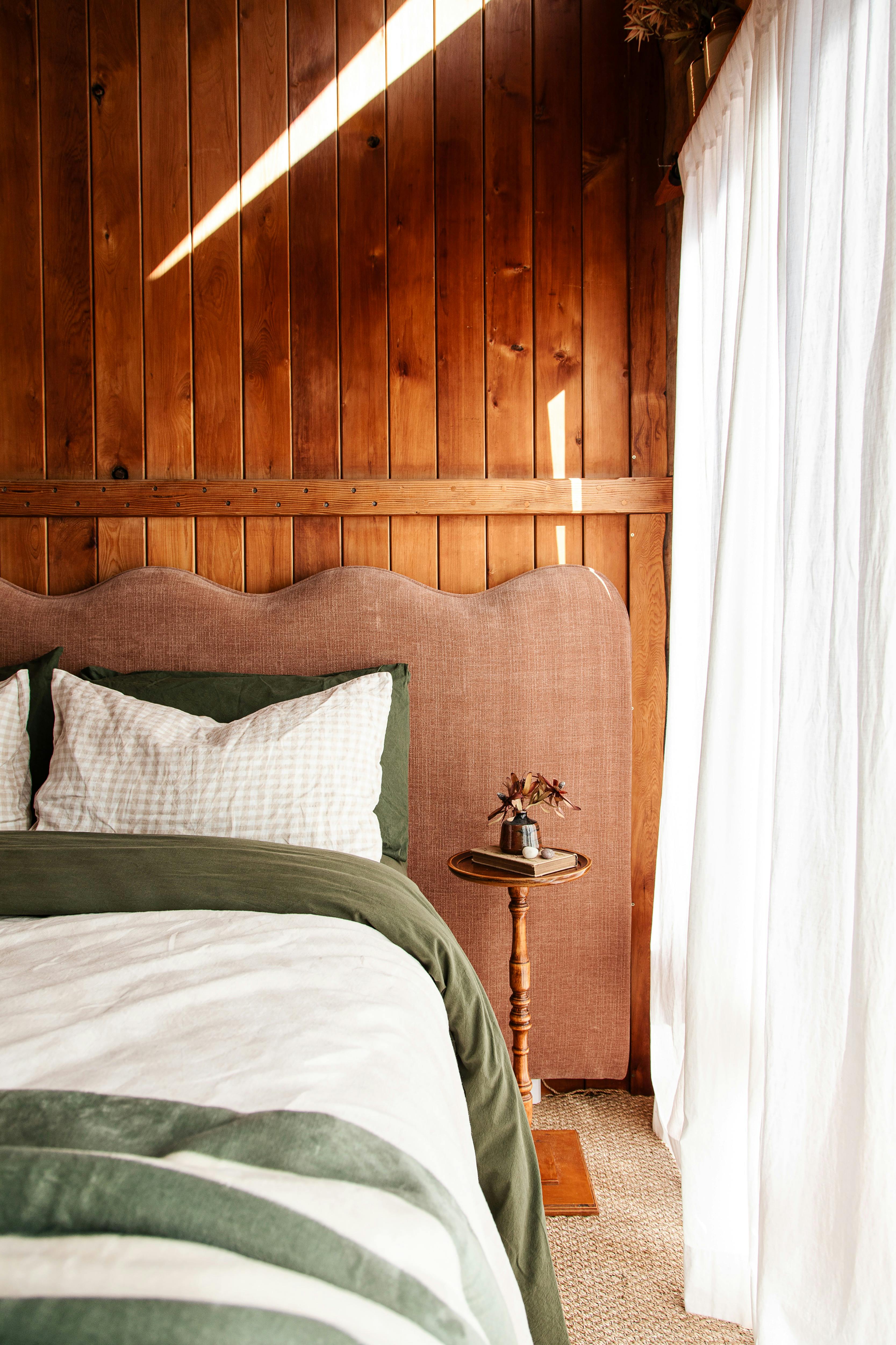 A cosy bed with bedhead draped in soft linen.