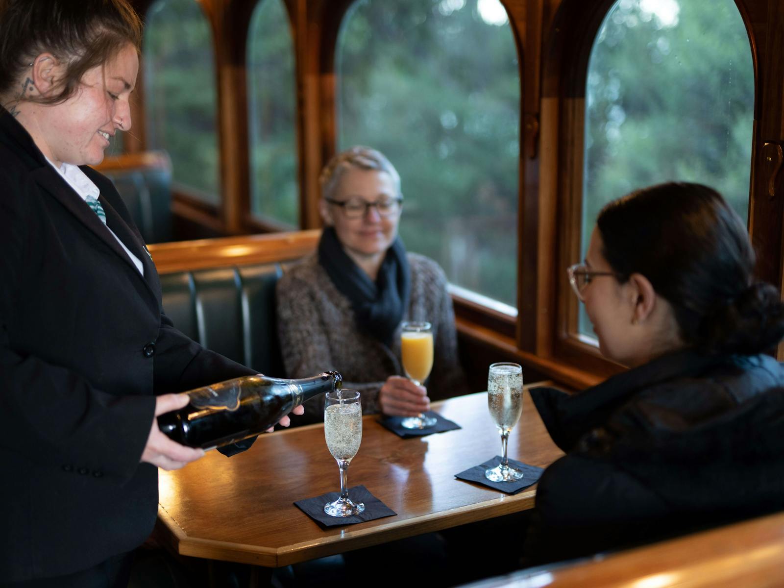 Steward pours sparkling wine for passengers onboard the wilderness carriage