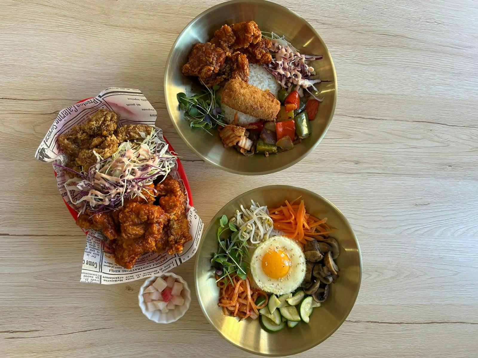 Korean fried chicken, rice bowls and sides served on a table, ready to share.