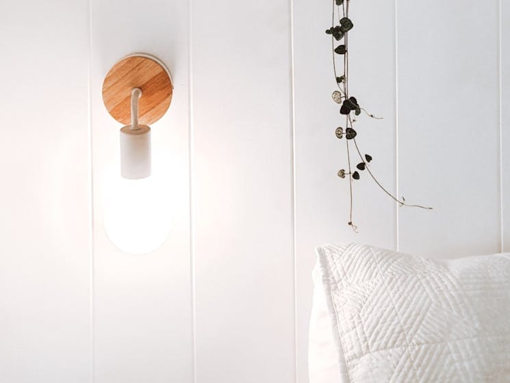 Close up of bedside light, white pillow and dangling green foliage