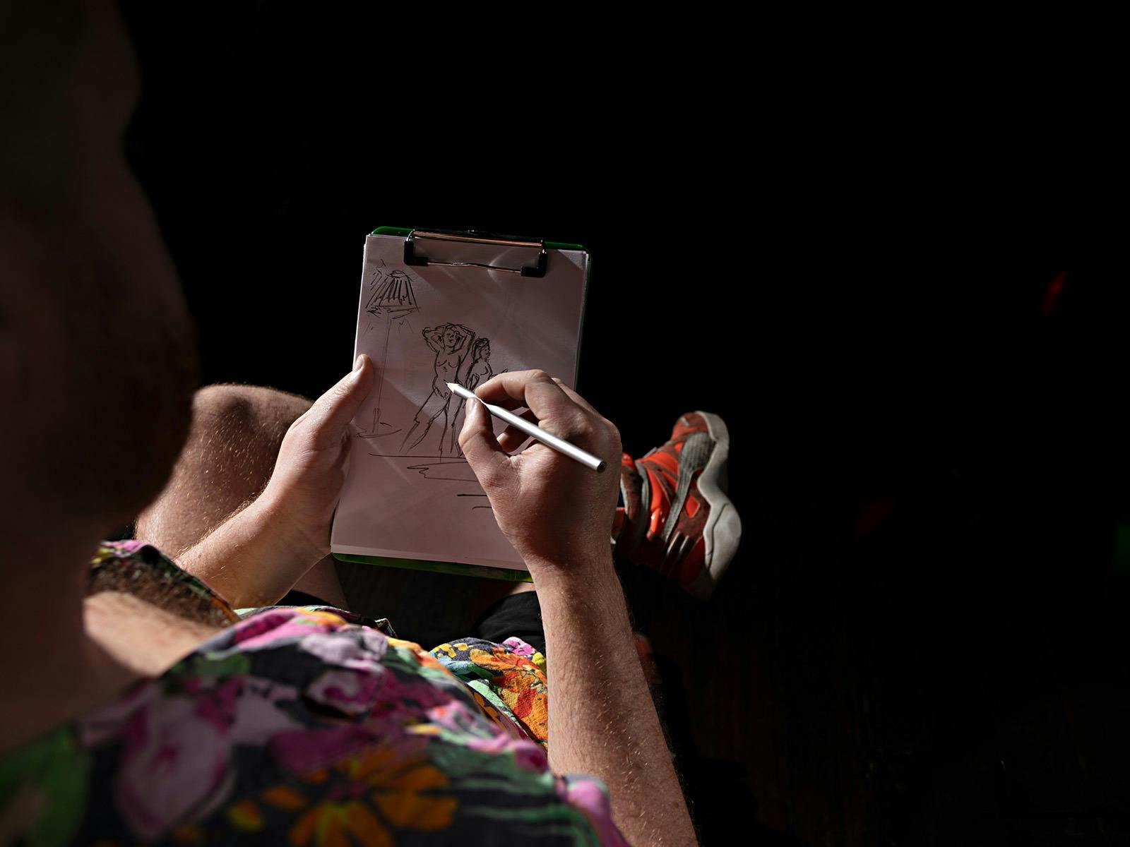 Person creating a figure drawing on a small notepad
