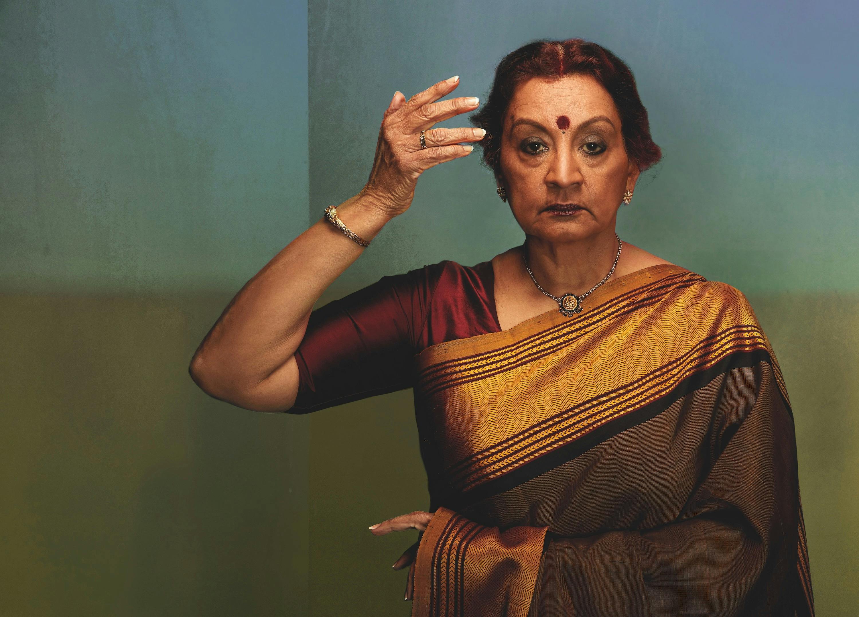 Elegant woman in a traditional saree, adorned with jewelry, holds a graceful pose.