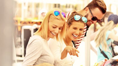 two women and a man smiling at lollies on display at a market stall