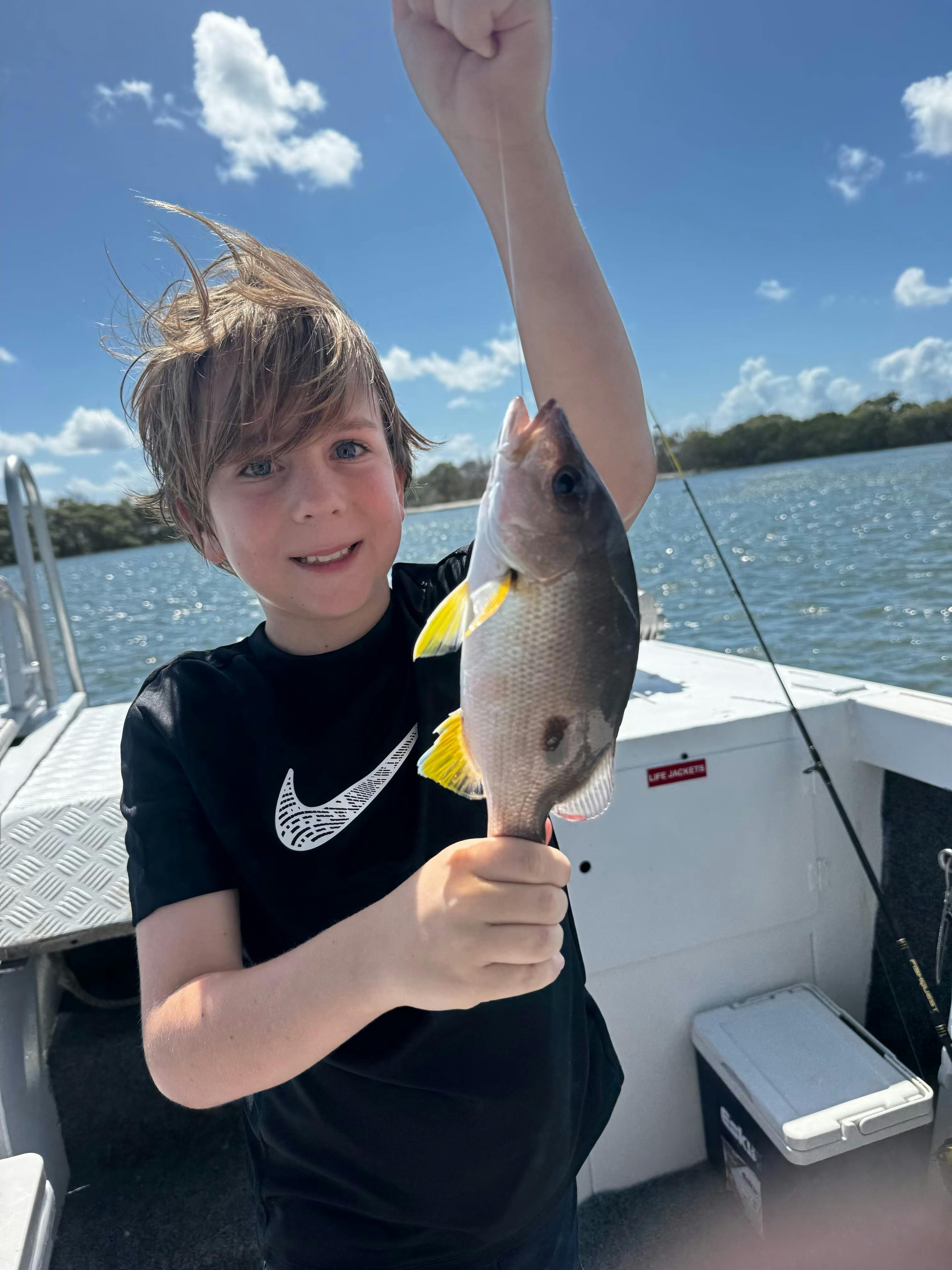 Young boy catches fish onboard Fish Moreton