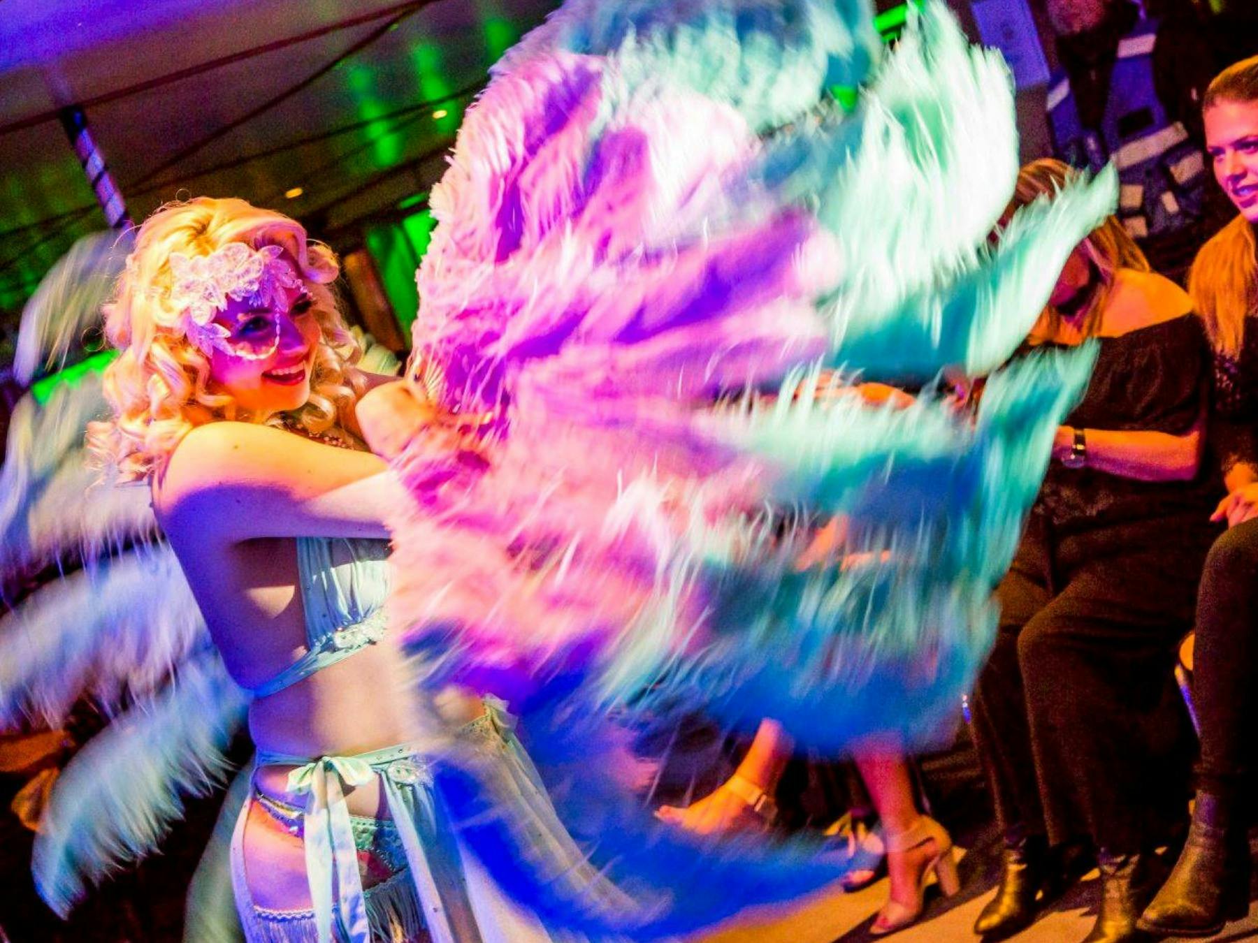 Poppy Cherry performing a feather fan dance in front of the audience.