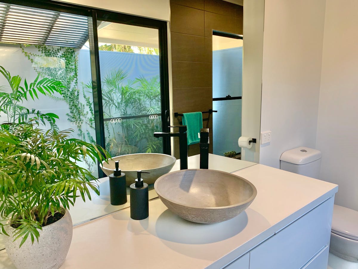 Ensuite showing basin and vanity with garden reflected in mirror