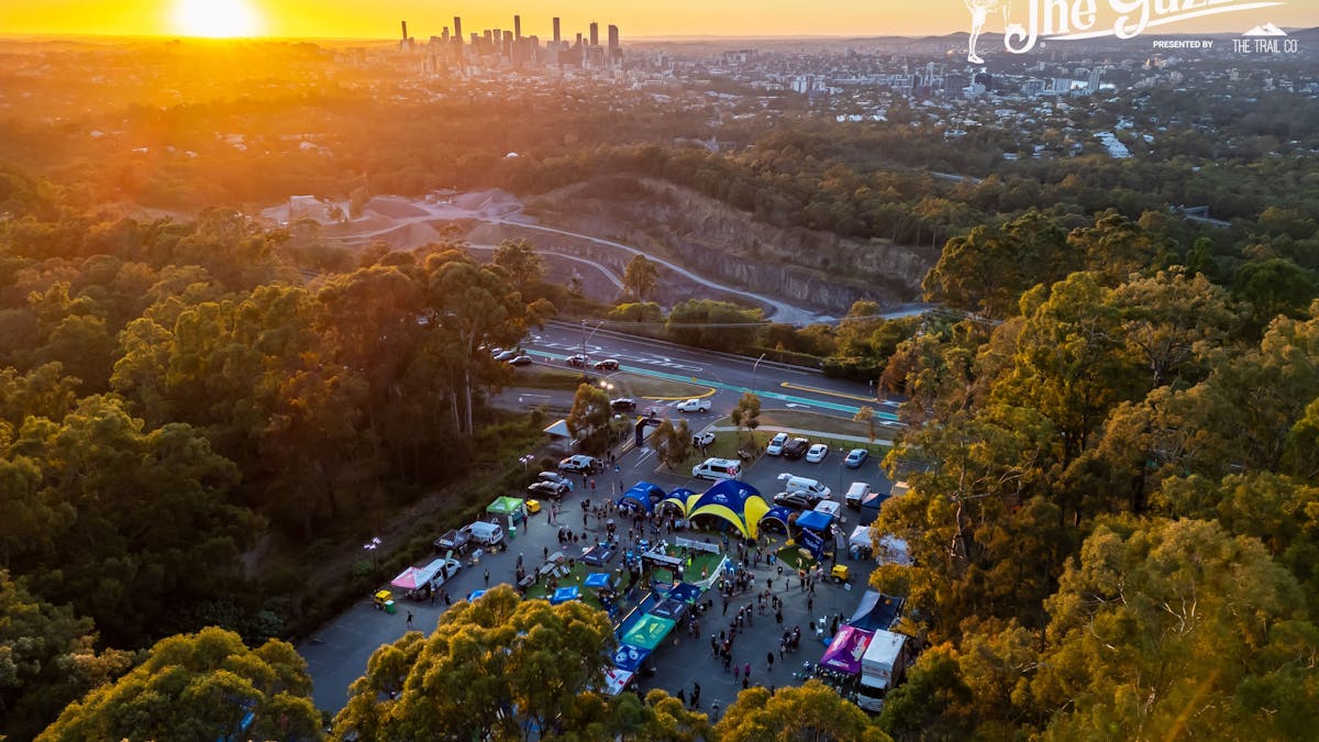 An aerial view of an event precinct with the sun rising behind Brisbane city in the background