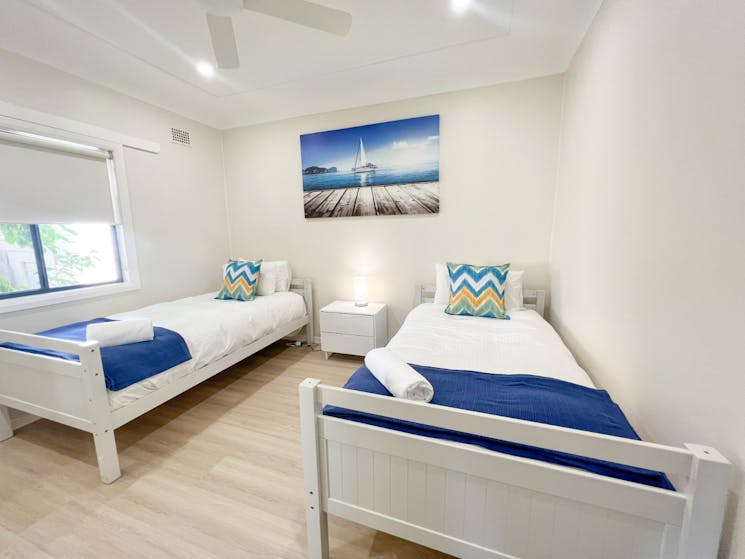 Bedroom 2 has two single beds with ceiling fan