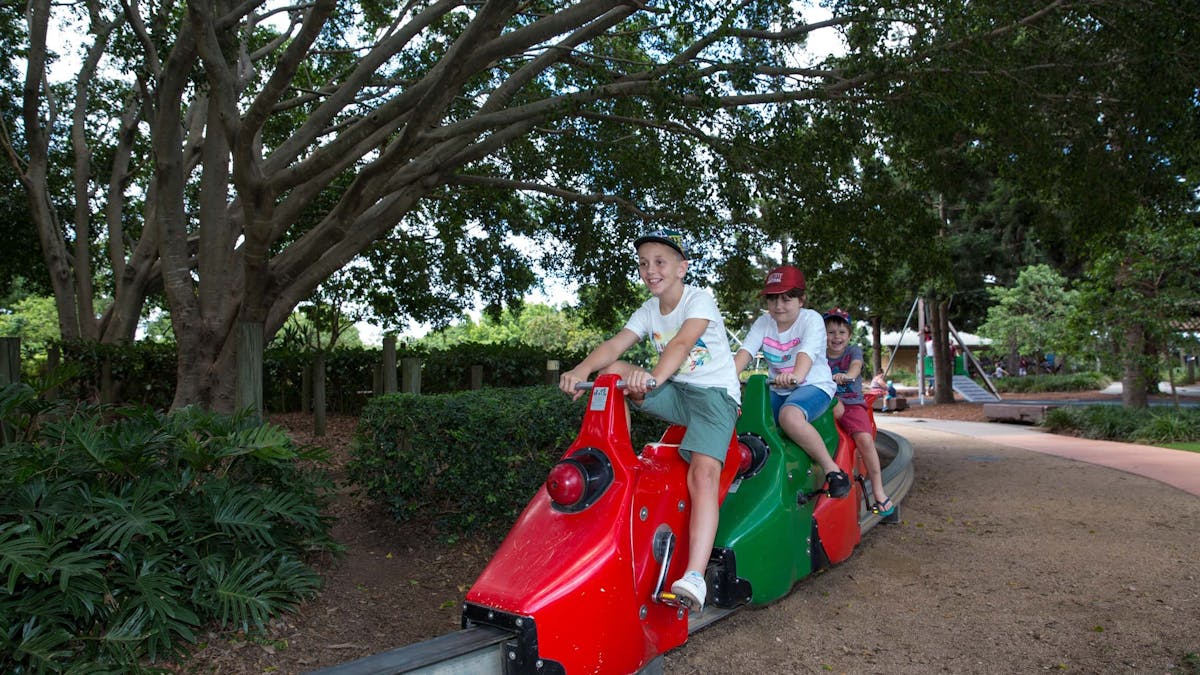 Two young boys on a pedal powered train in park