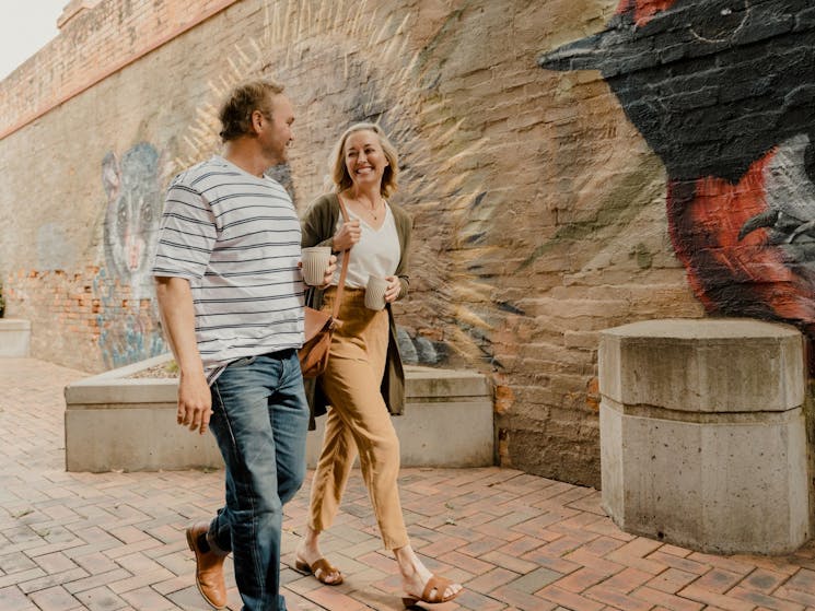 couple walking past native animal mural