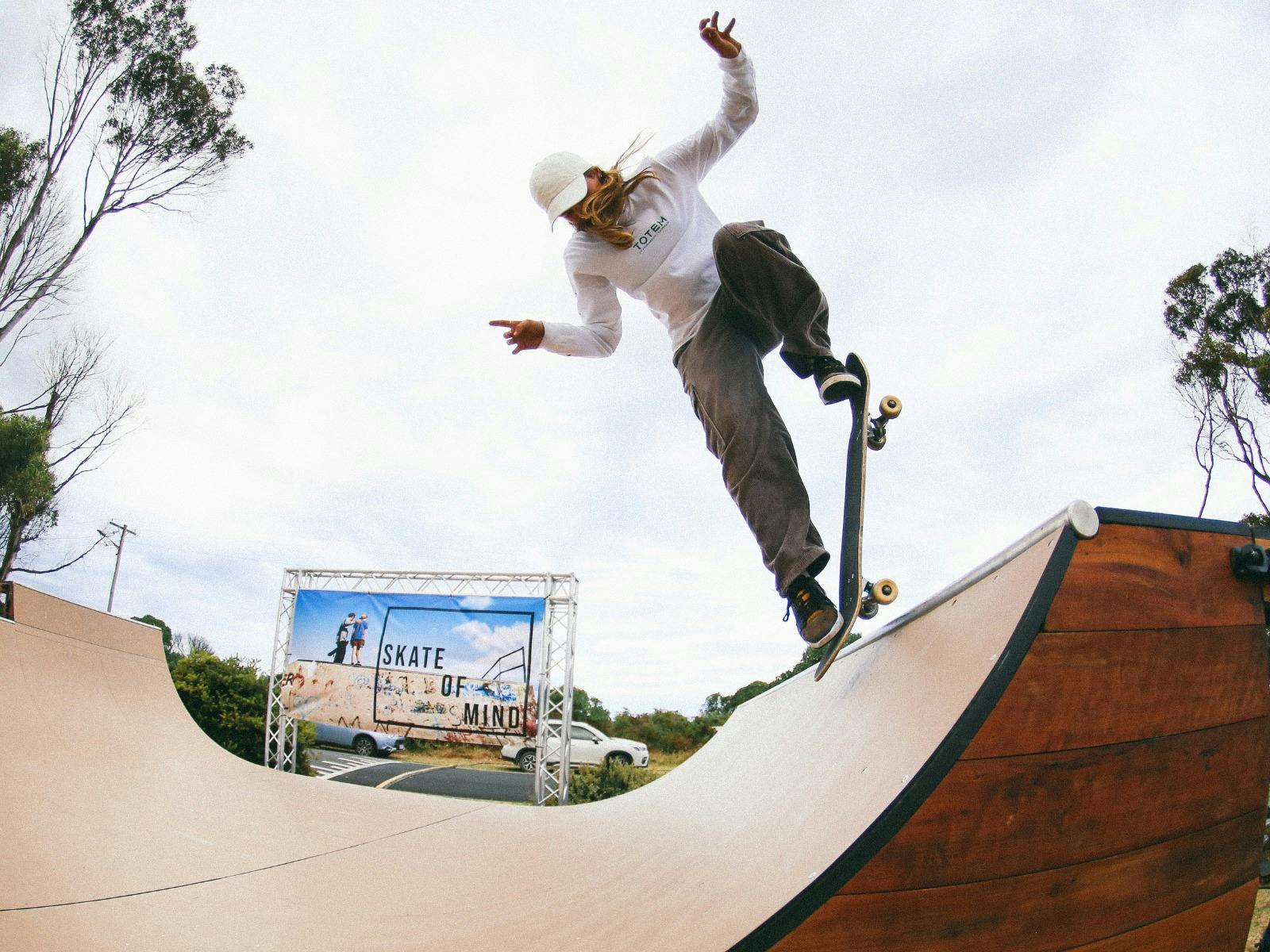 female skateboarder tricks out at the top of the mobile half pipe