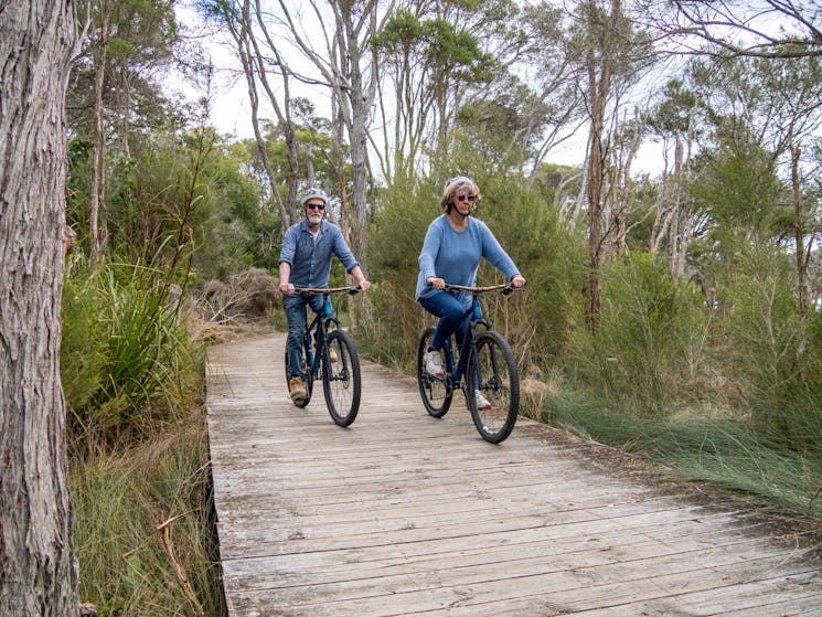 Two guests cycle along the baord walk