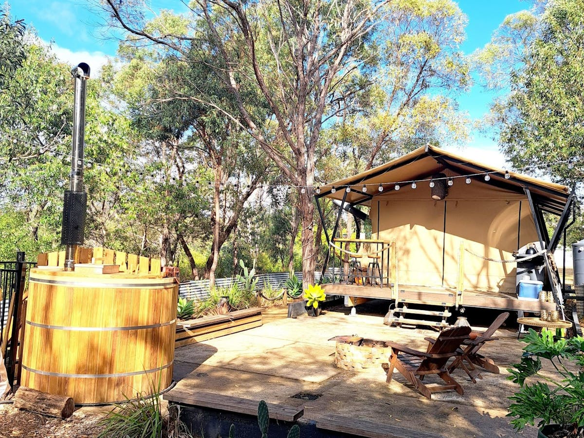sarafi canvas tent set in bush with a round wooden hot tub with chimmney in foreground sarafi canvas tent set in bush with a round wooden hot tub with chimmney in foreground