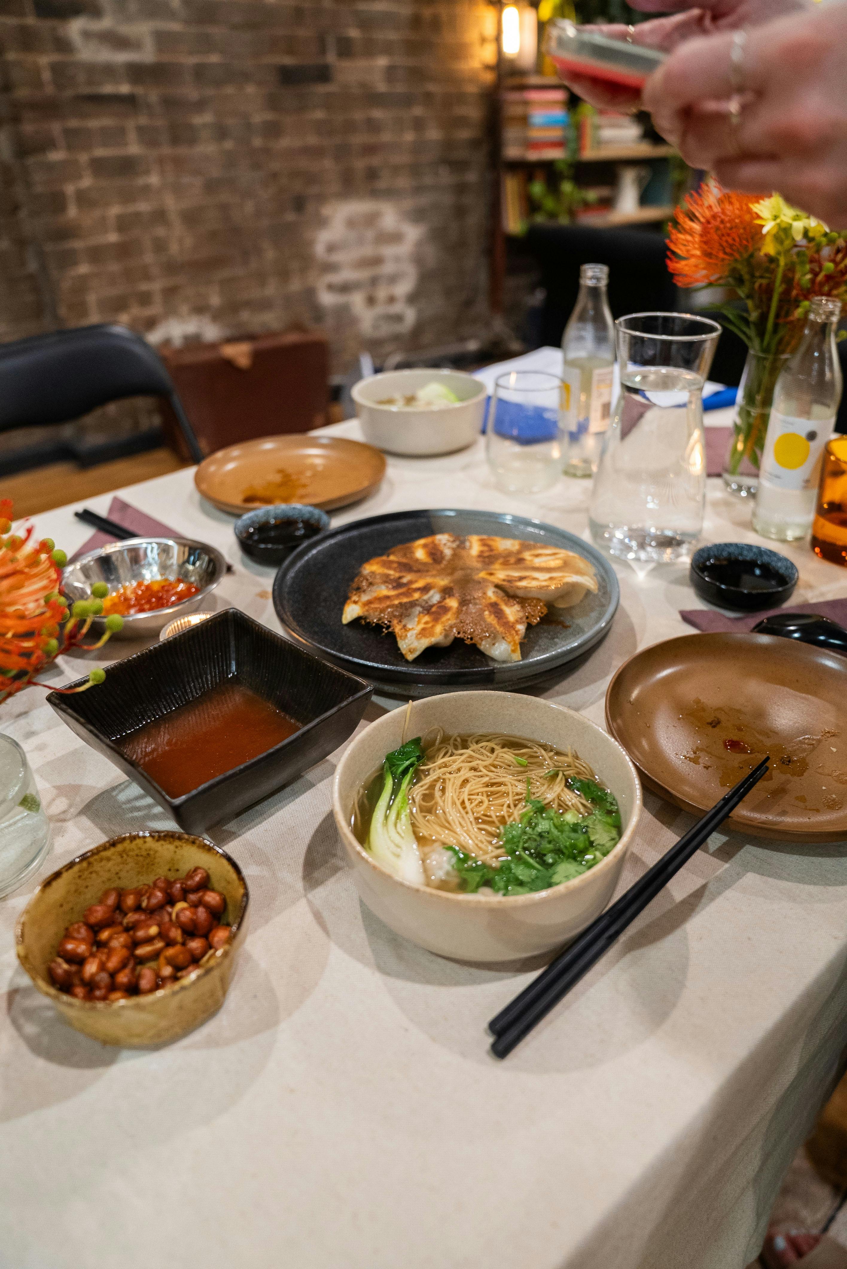 A set table with plates and bowls full of dumplings and colourful flowers
