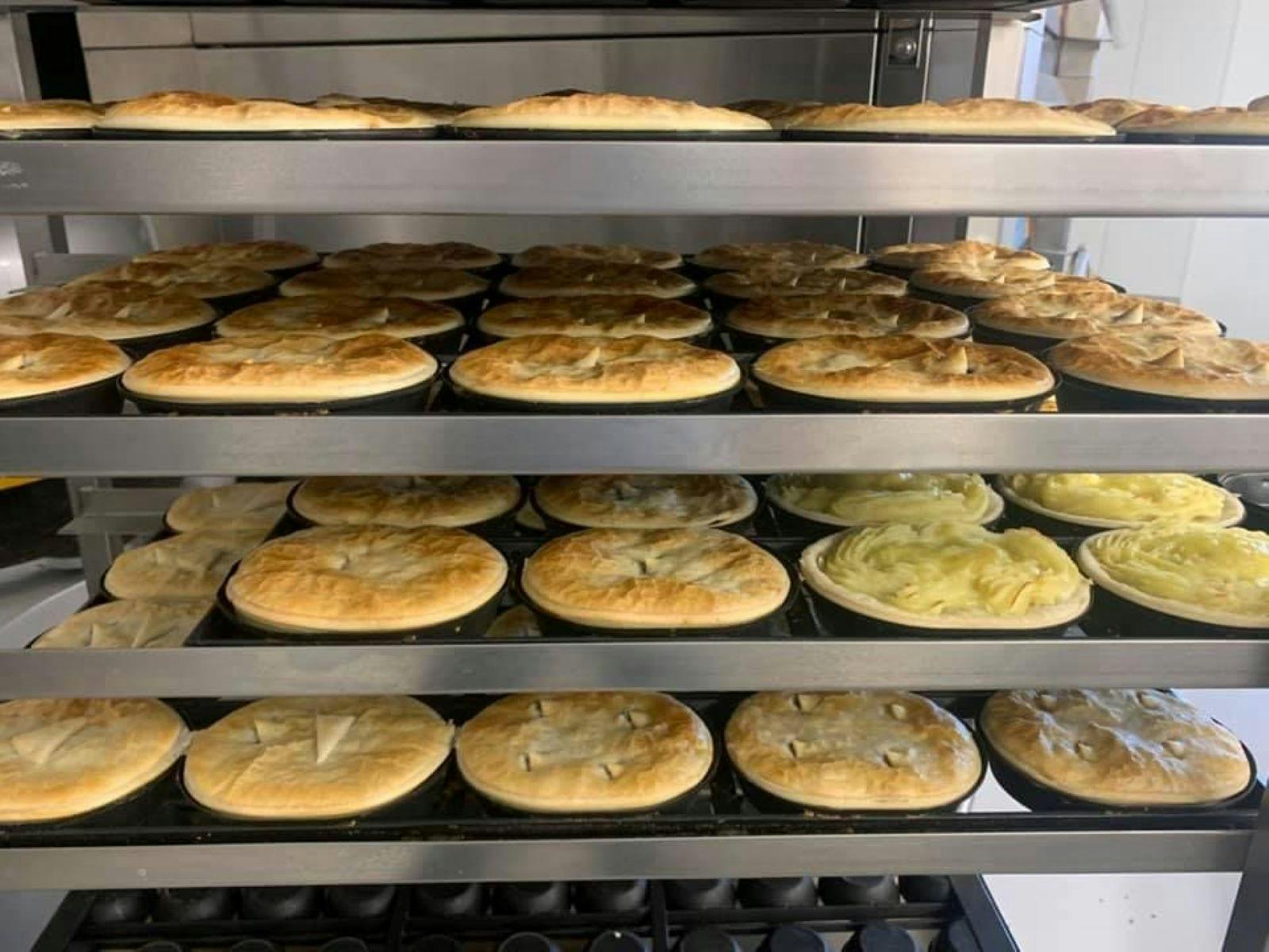 Lots of fresh pies, all different flavours, sitting in rows in a pie warmer.