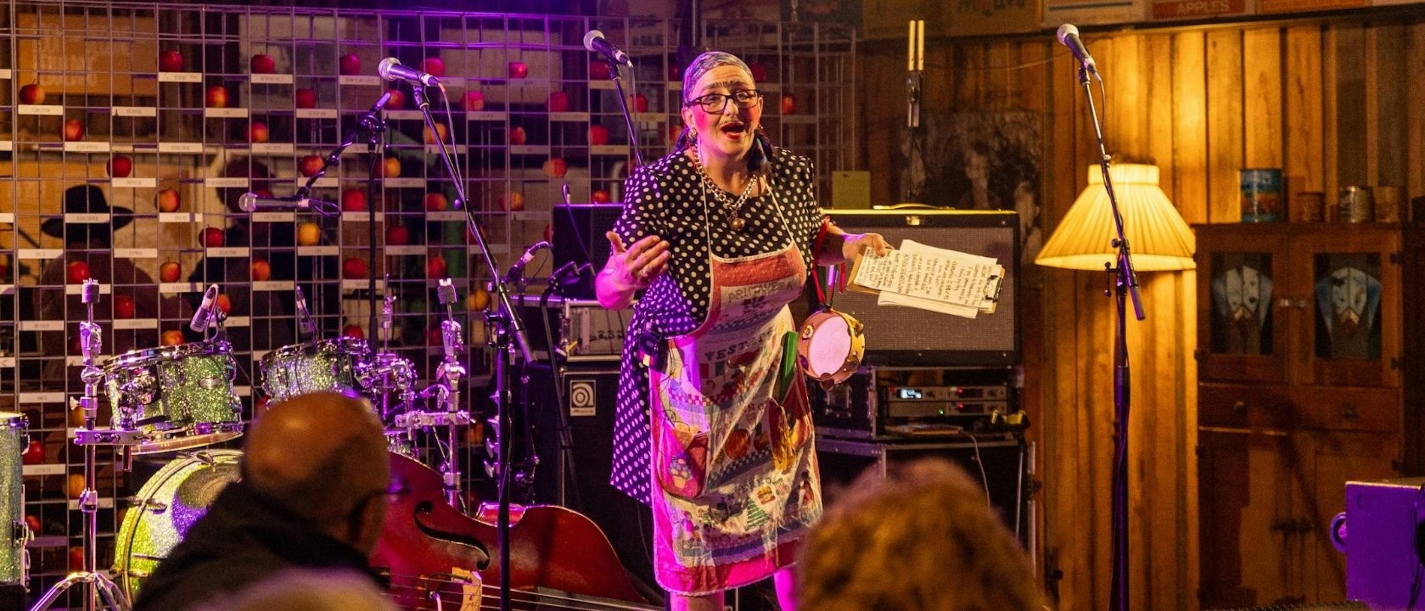 A woman wearing a dress and apron on stage