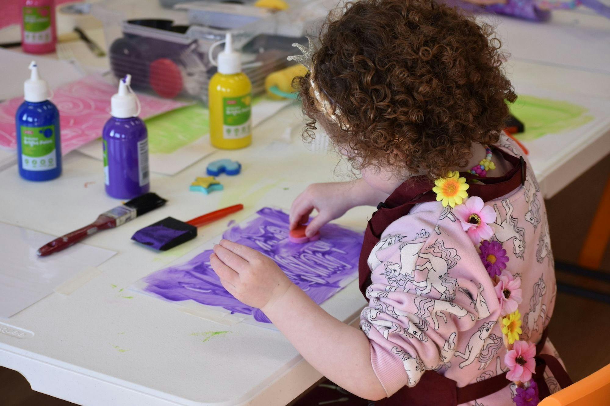 4 year old child painting and stamping with purple paint
