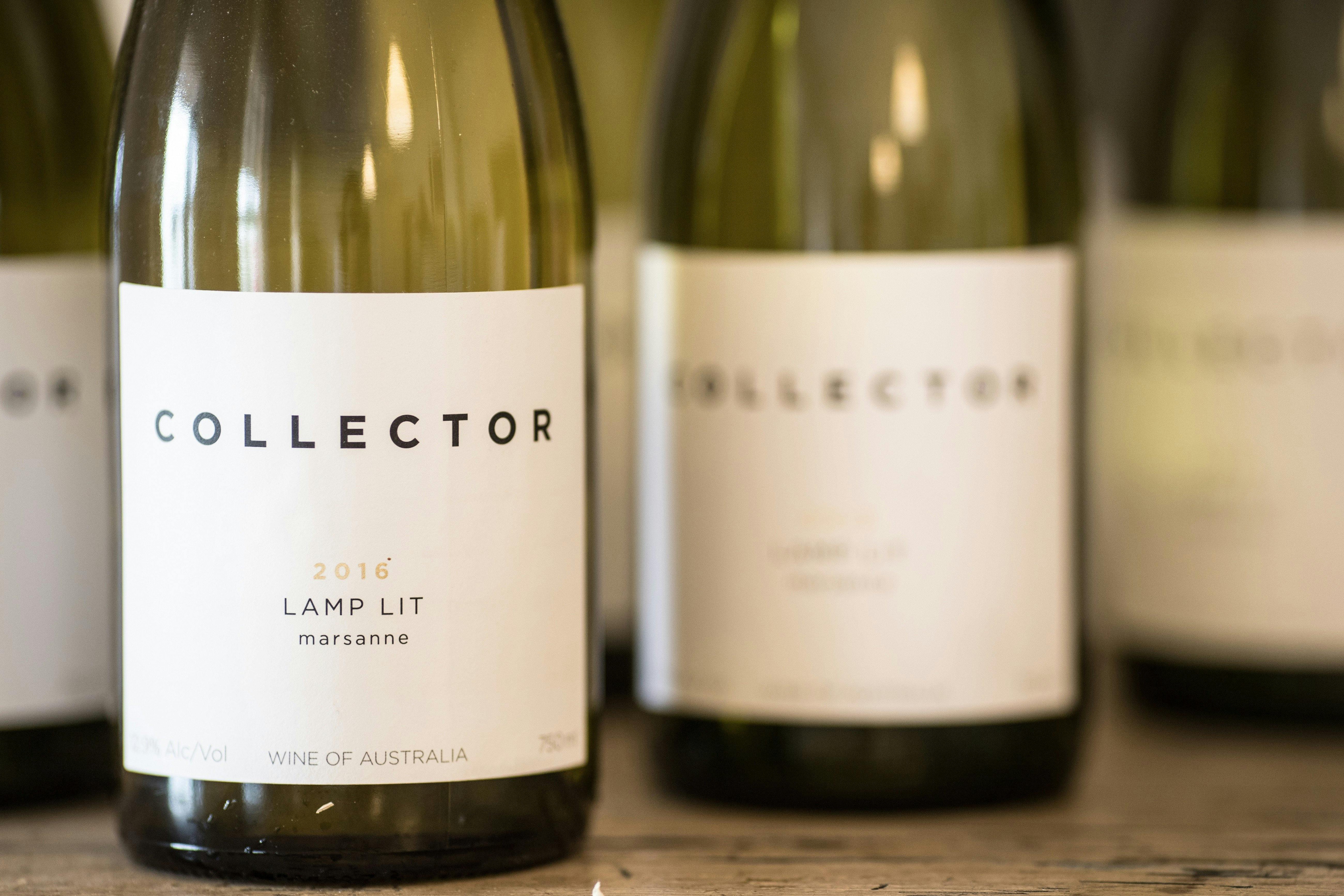 White wine bottles are lined up. The label reads, Collector, Lamp Lit Marsanne 2016.