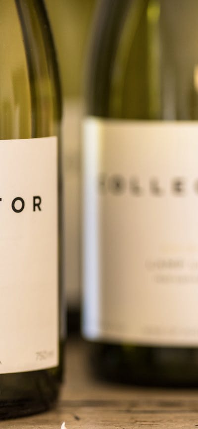 White wine bottles are lined up. The label reads, Collector, Lamp Lit Marsanne 2016.