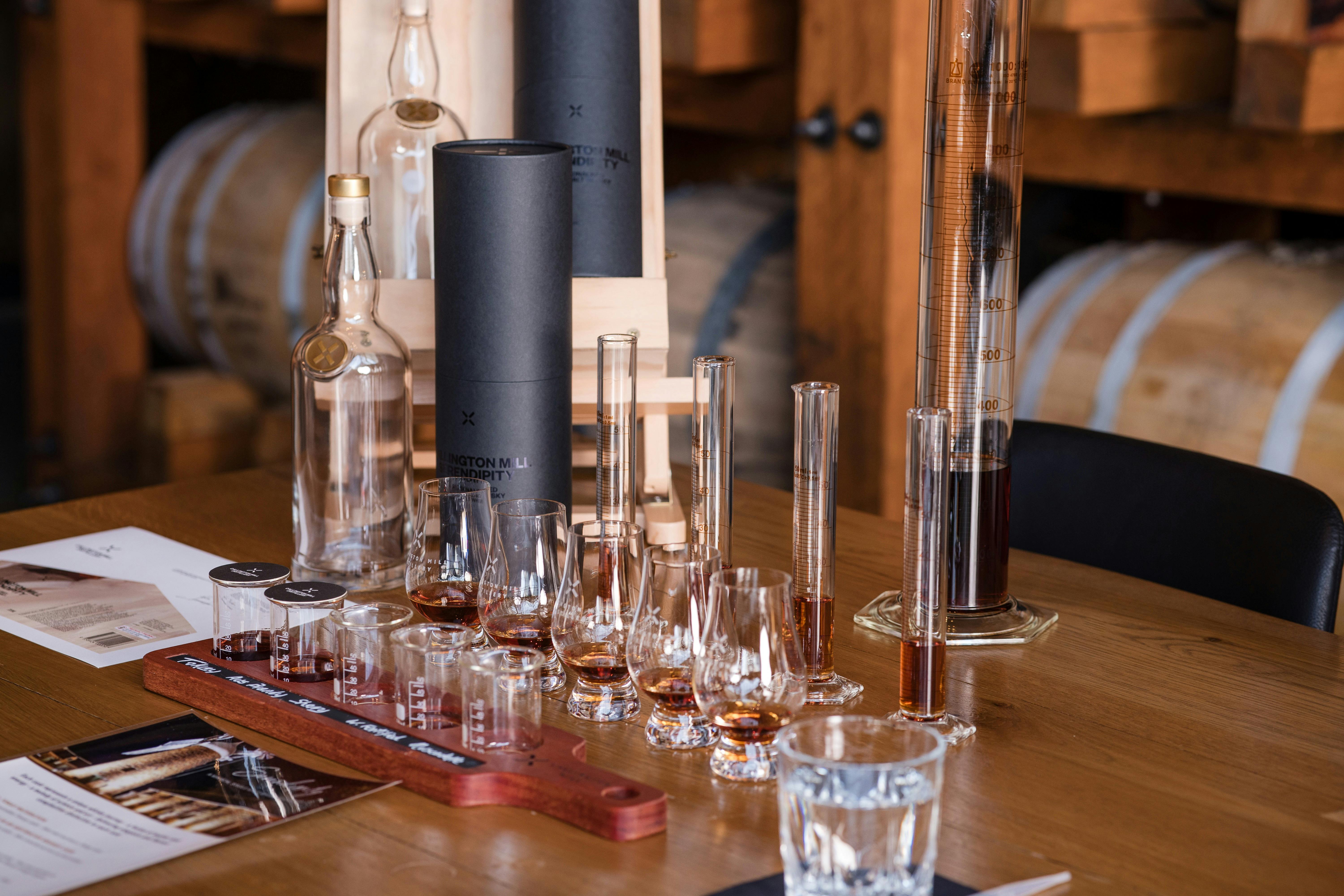 A paddle of whisky glasses with an empty bottle  and blending instruments