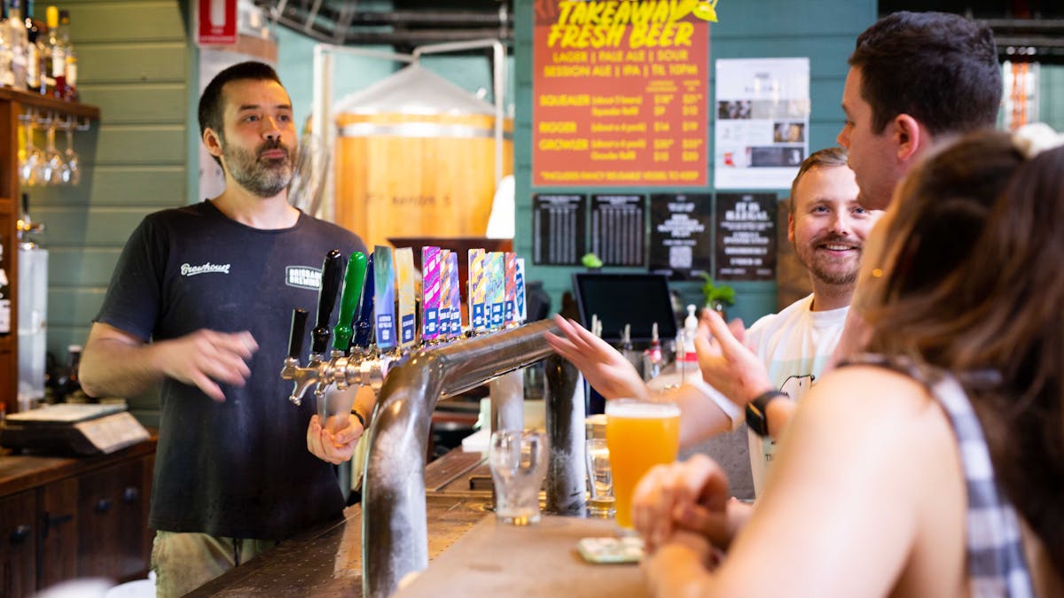 three customers chat to the brewer over the bar.