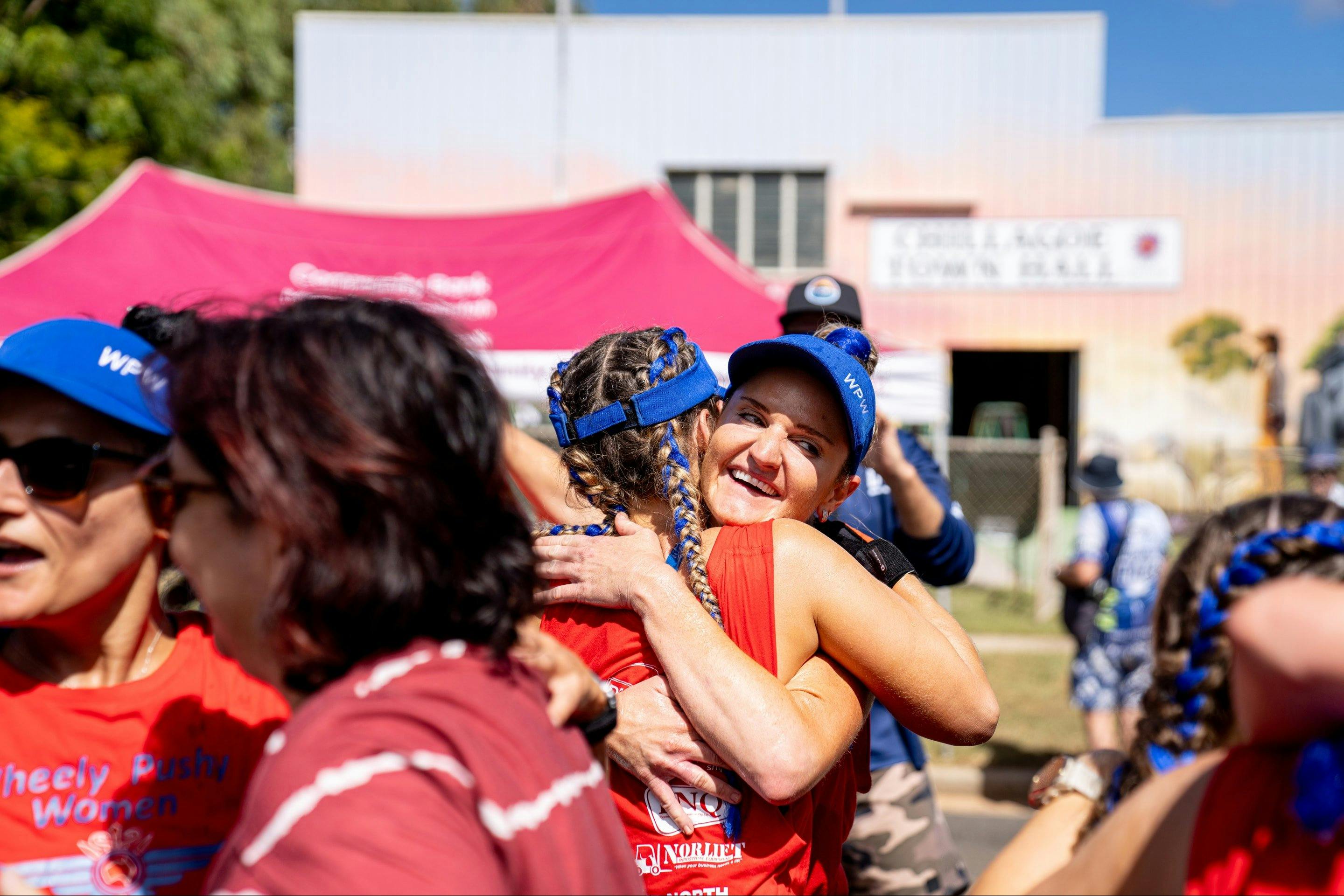 Two woman embrace to celebrate their Great Wheelbarrow race achievements.
