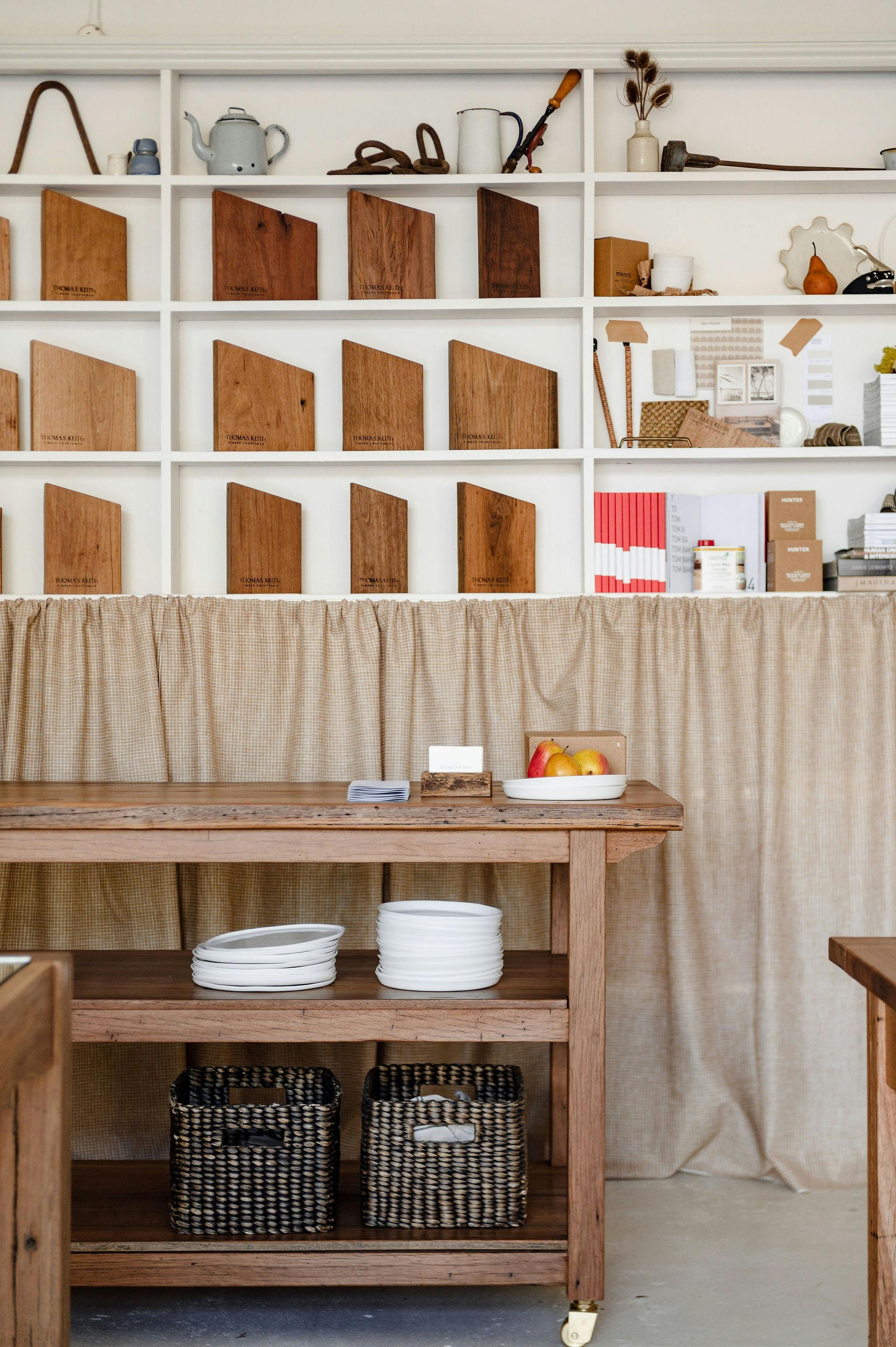 Timber samples on shelves, island bench with ceramics on it as a place to discuss designs.