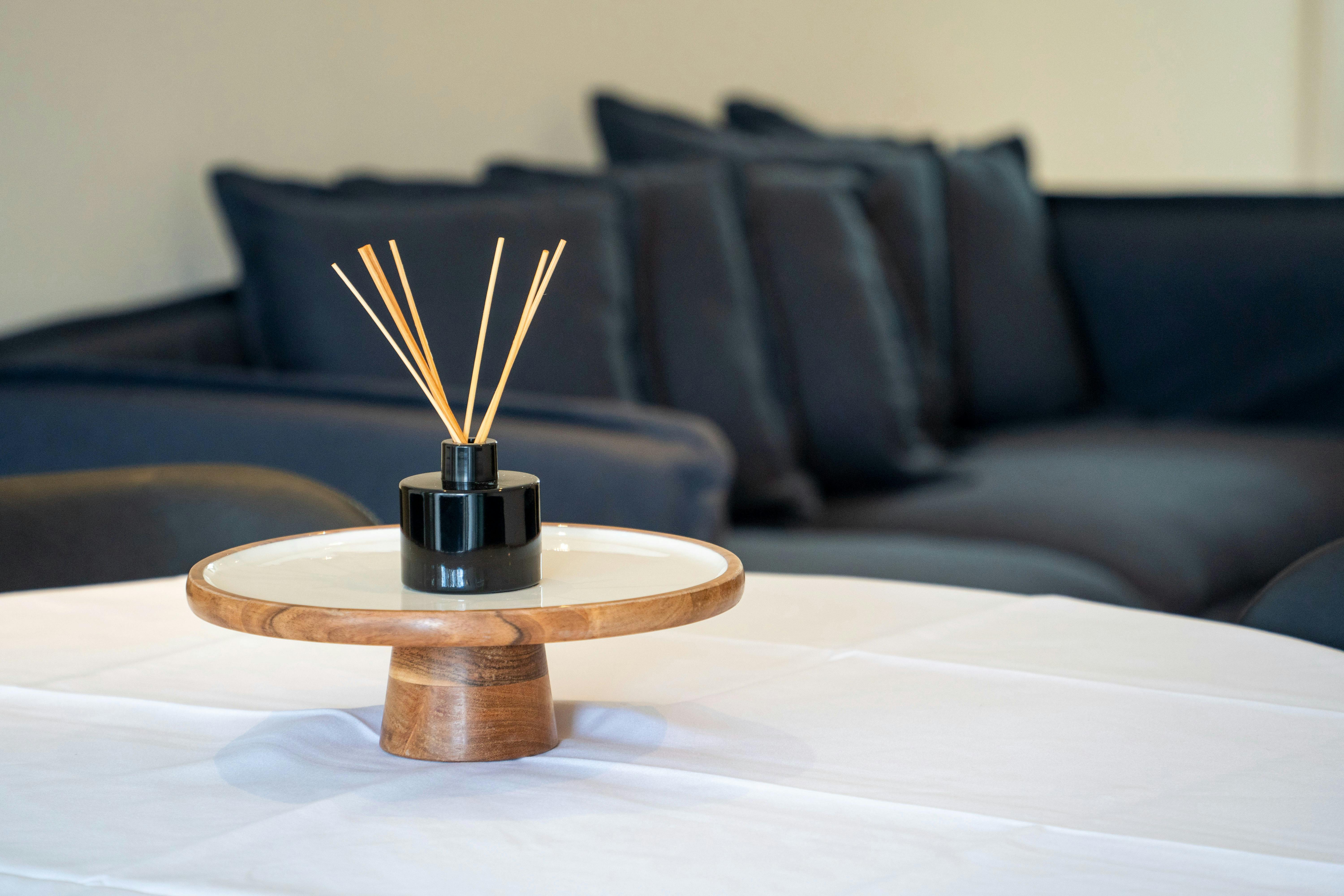 Stylish room diffuser on a dining table with cozy seating in the background.