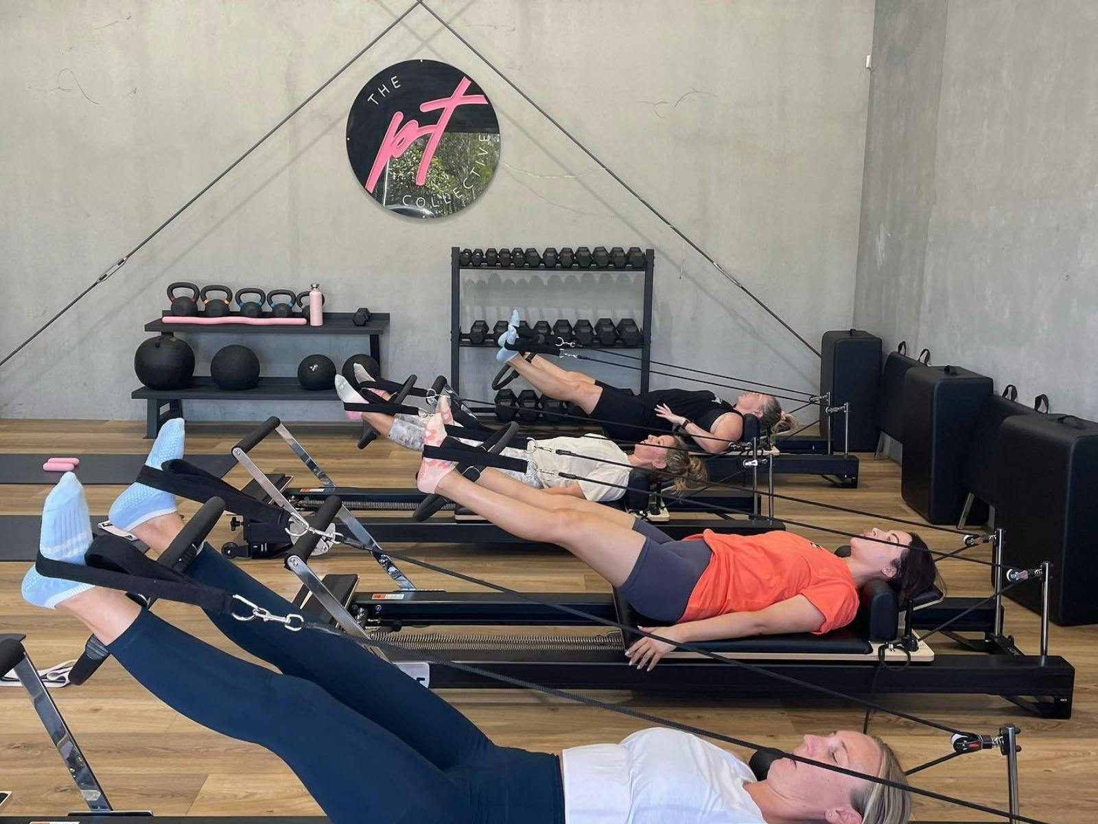 Women doing a reformer Pilates class in a sleek modern studio.
