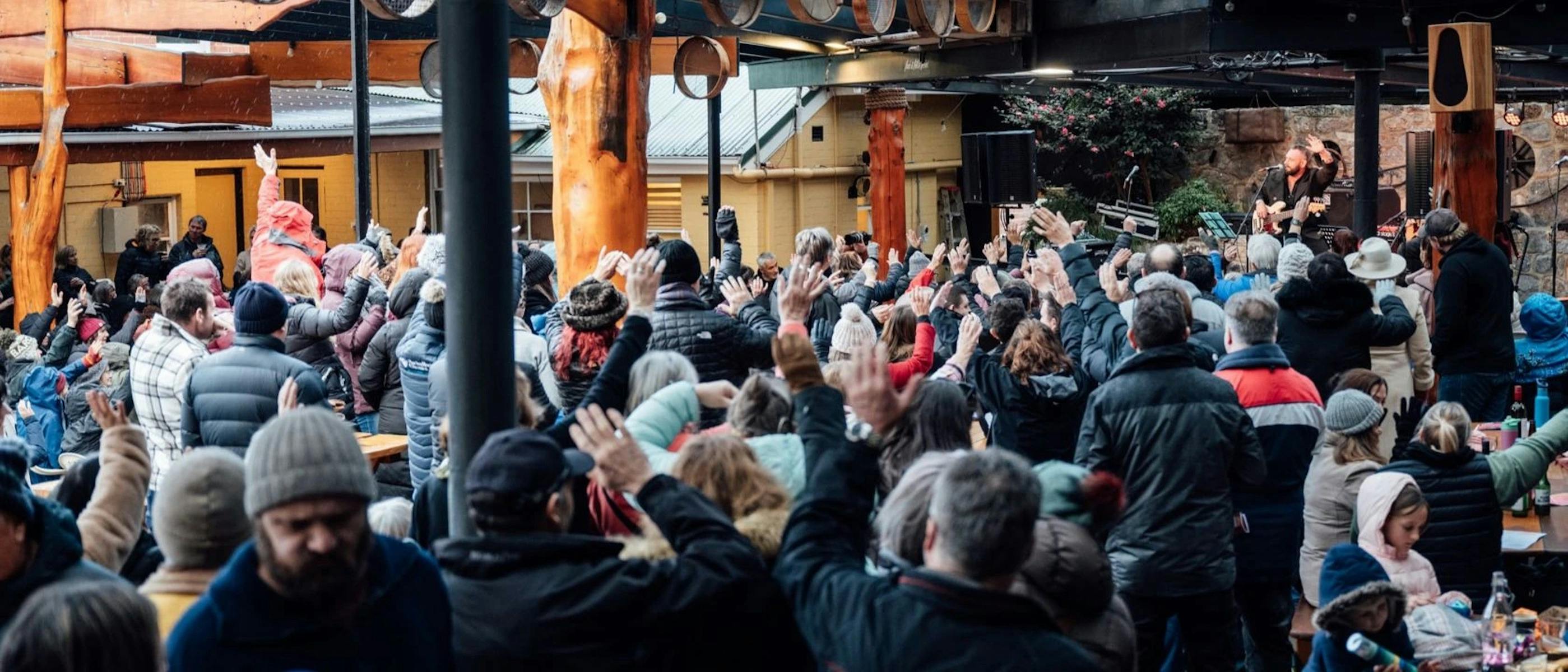 A group of people dancing outdoors in front of a stage