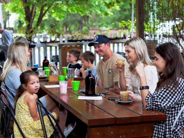 Family group, dining in the leafy courtyard, drinking coffee.