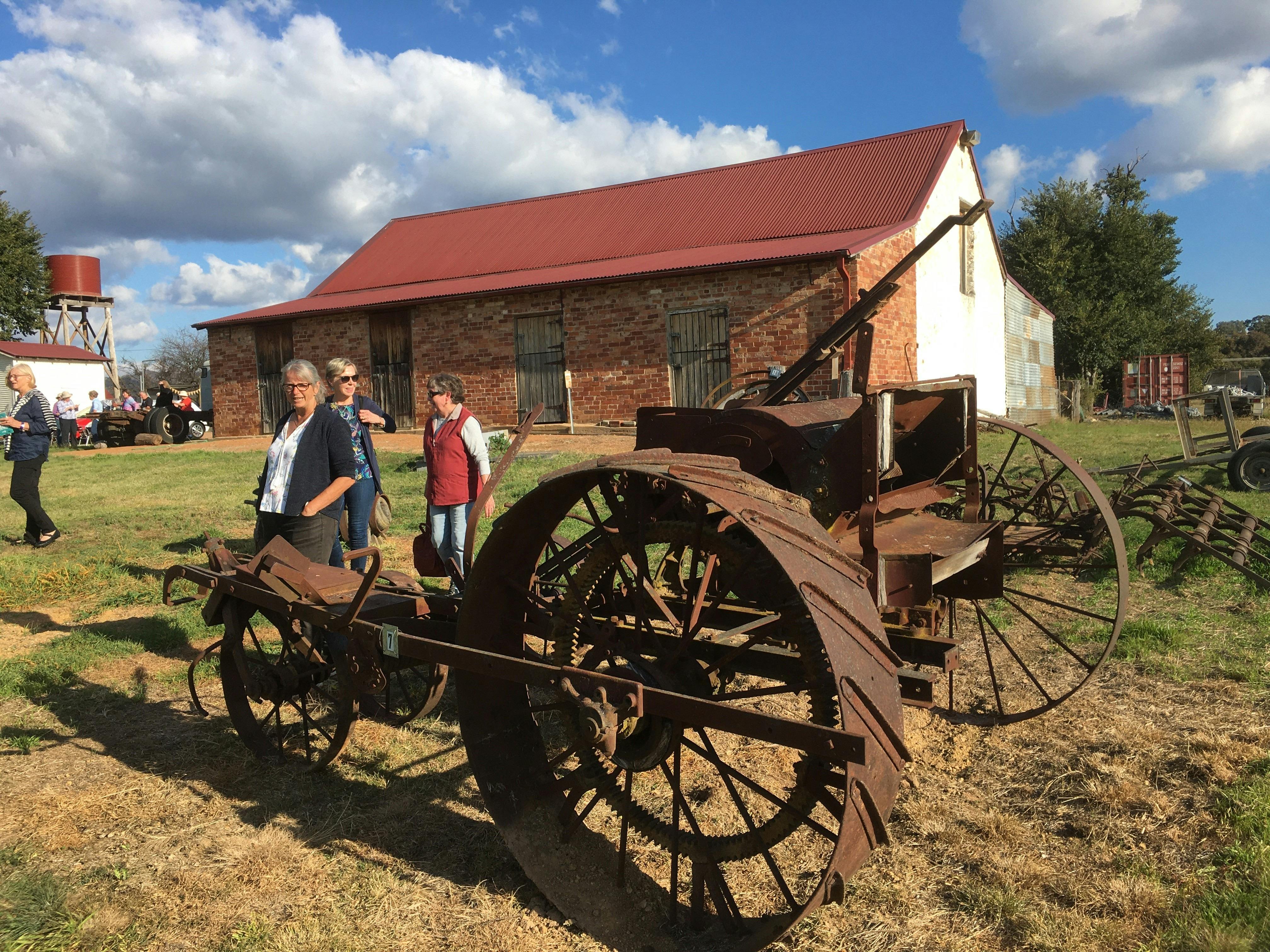 Rusted old plough with 3 people behind.
