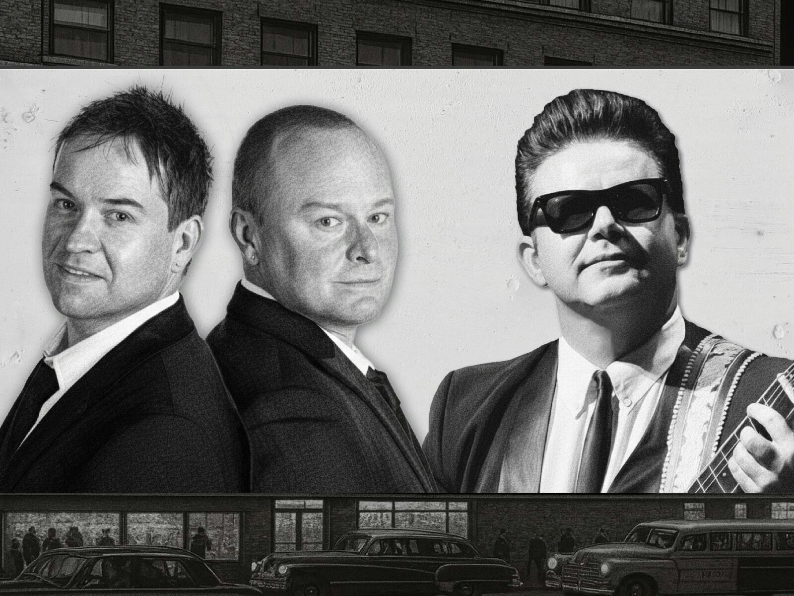 Three men in black suits, one with sunglasses, look at the camera against a grey backdrop