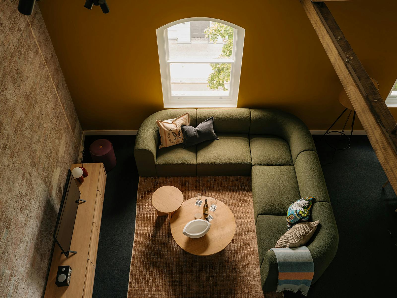 Overhead view of living room with sage green corner sofa and round coffee table.