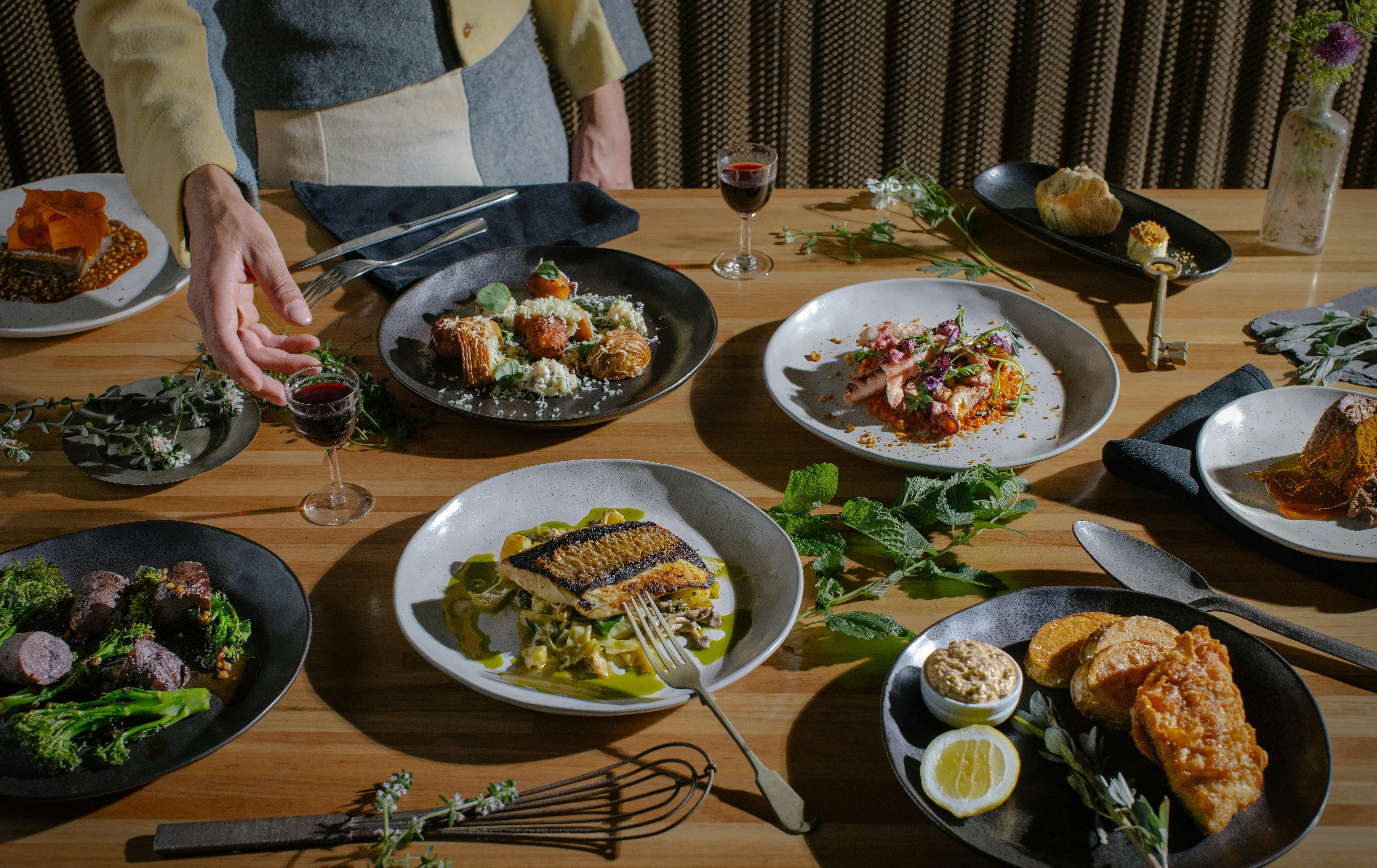 Person reaching for plated dishes on a dining table