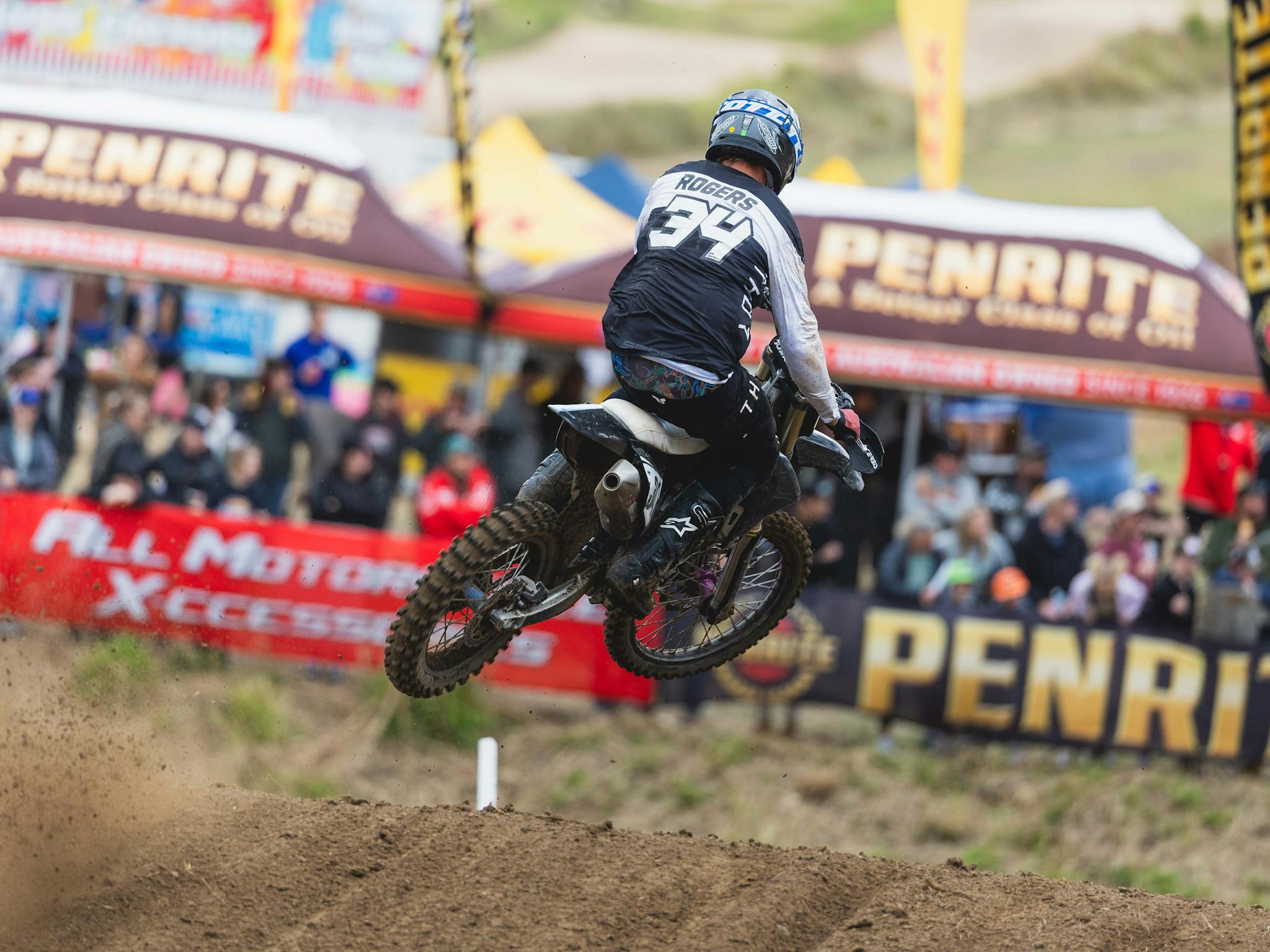 A rider soars through the air while spectators watch on in the background A rider soars through the air while spectators watch on in the background