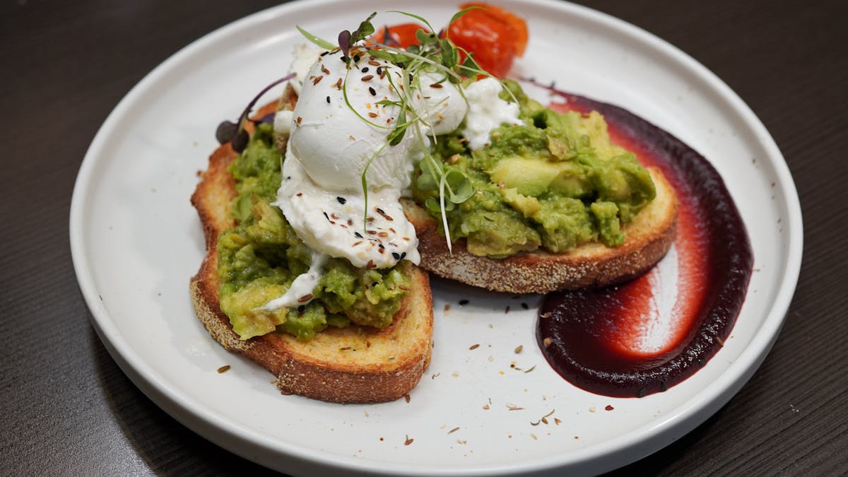 A breakfast order with smashed avocado and poached eggs on toast