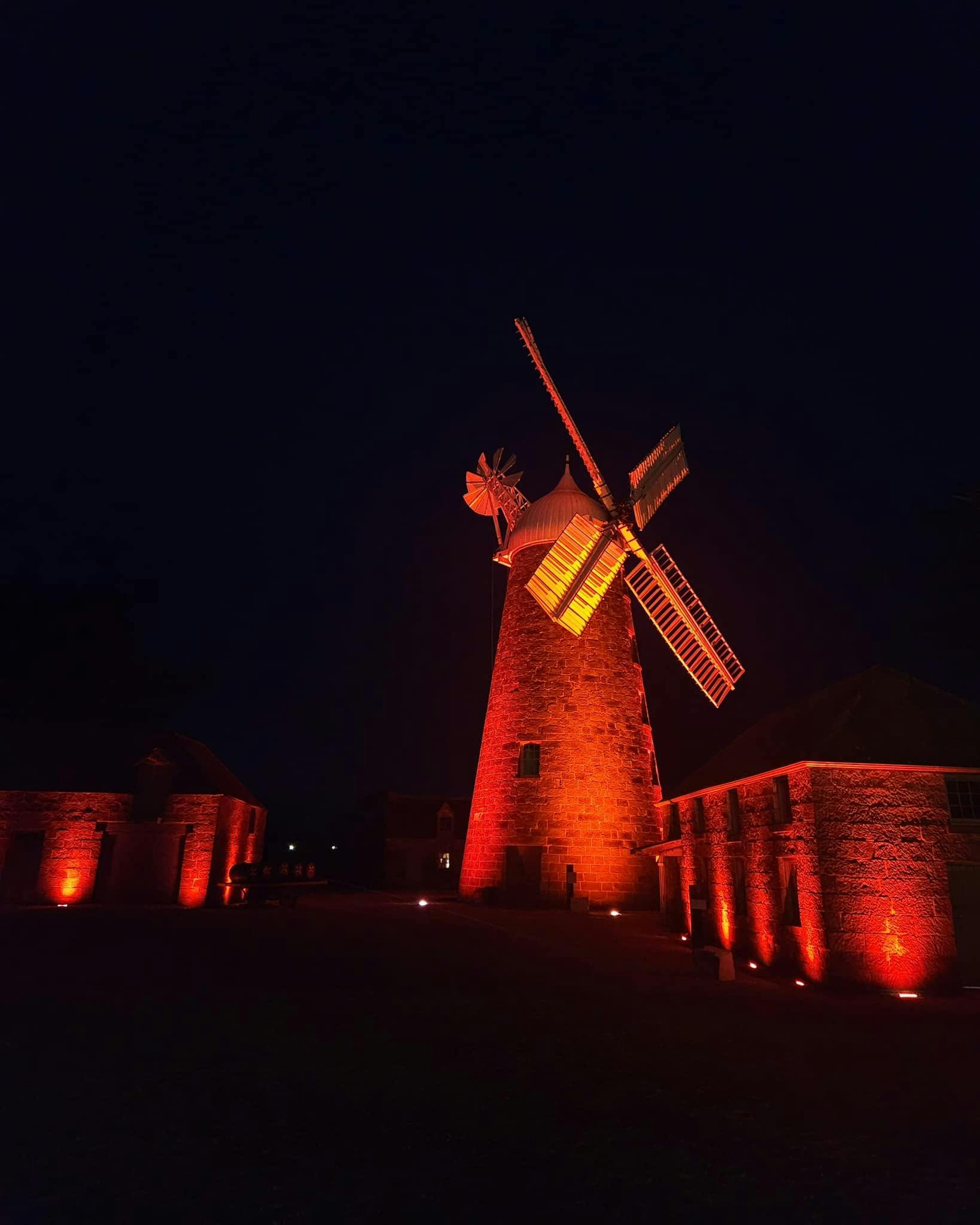 A windmill at night lit up with red lights