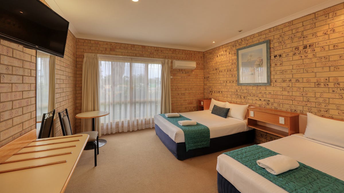 Room photo showing 1 queen and 1 single bed, bench, chairs and window