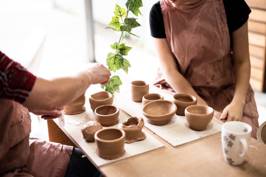 Picture of two people and finished clay pots on a bench
