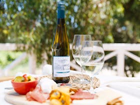 A bottle of Ashton Hills Estate Riesling with two glasses and a cheese board