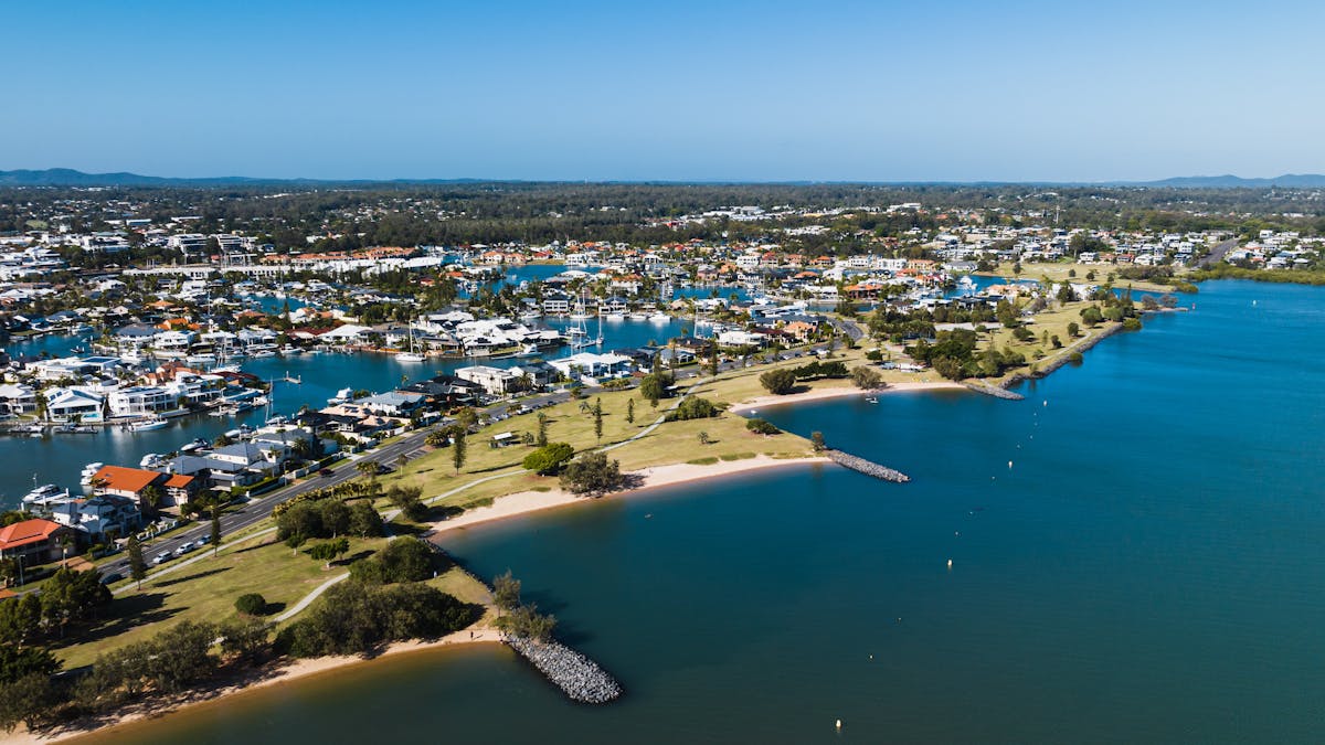 Aerial view of Raby Bay Foreshore Park, surrounded by housing, clear blue skies and canals.