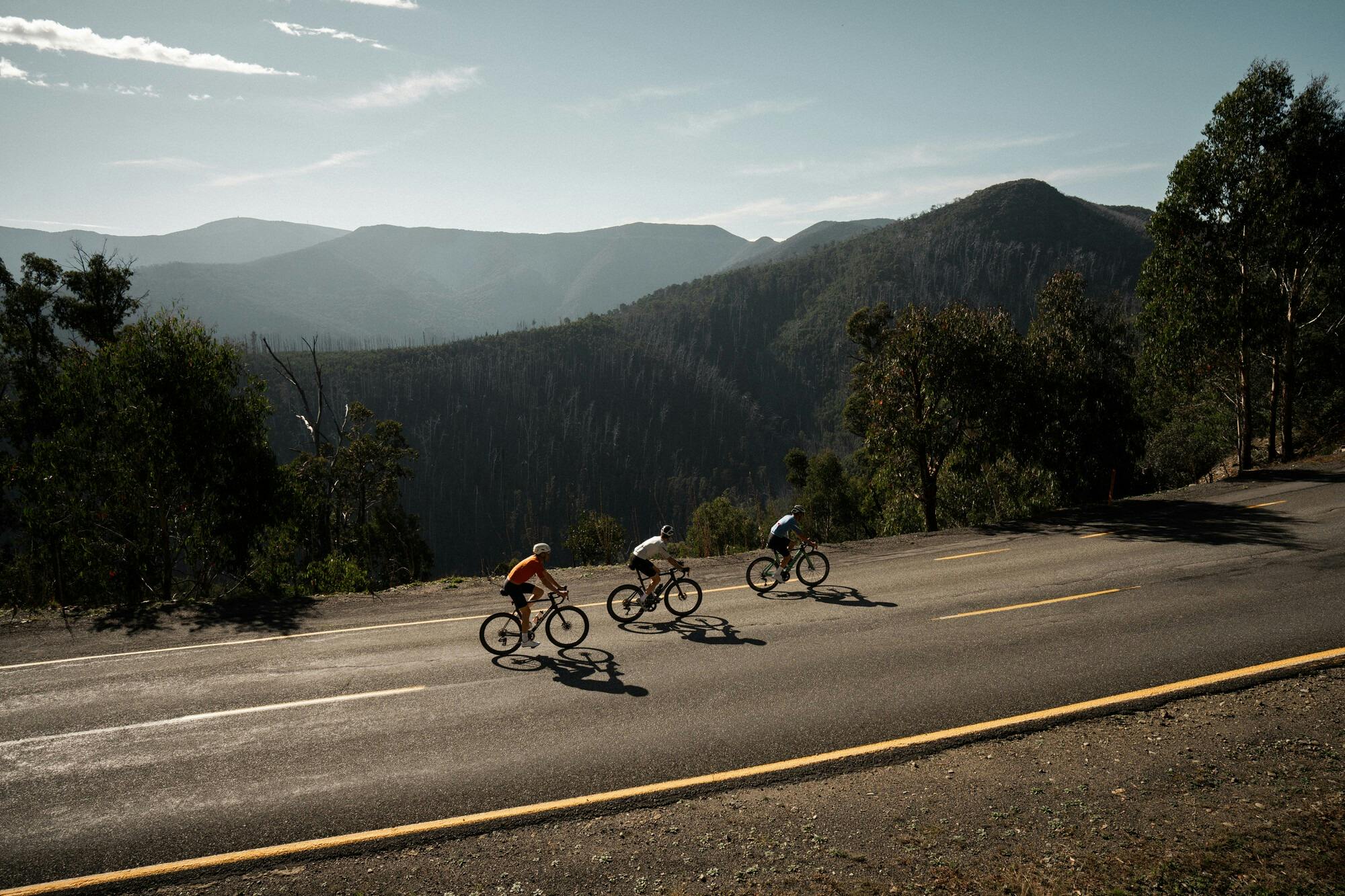 Three cyclists riding past mountain views on the Mt Hotham 7 Peaks Challenge route