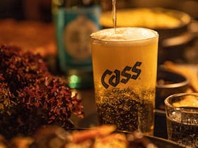 Pouring a Korean beer called Cass into a glass.